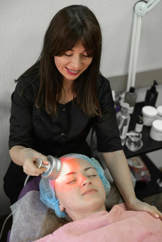 Woman receiving a facial treatment using a red light therapy device.
