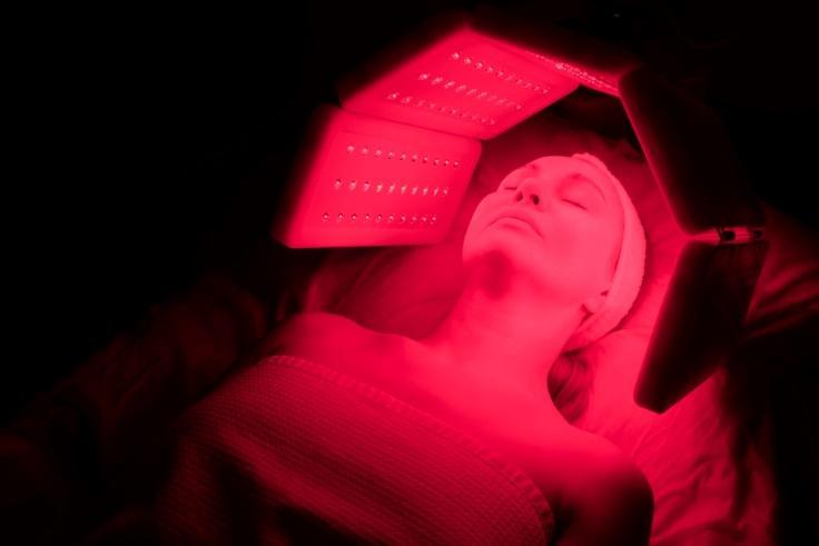 Woman under a red light device at a clinic