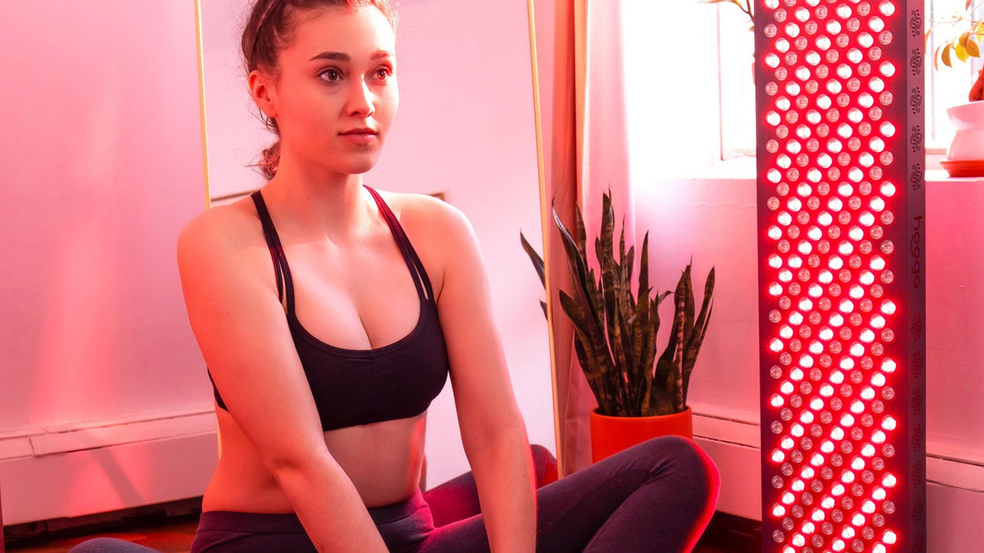 Woman sitting cross-legged in front of a Hooga red light therapy panel