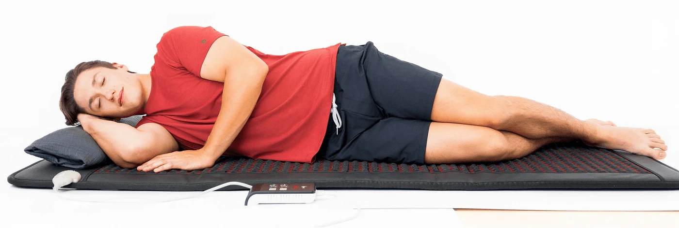 A man resting on the Hooga PEMF mat with infrared heat